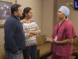 Healthcare provider talking to man and woman in hospital waiting room.