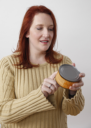 Woman reading nutrition label on can.