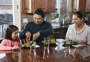 Man, woman, and girl eating healthy food at home.